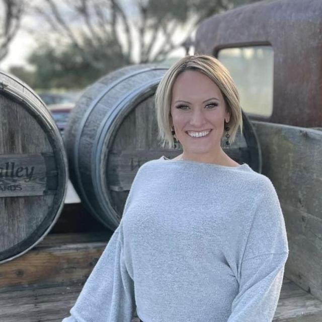 Natalie Frazier in front of wine barrels