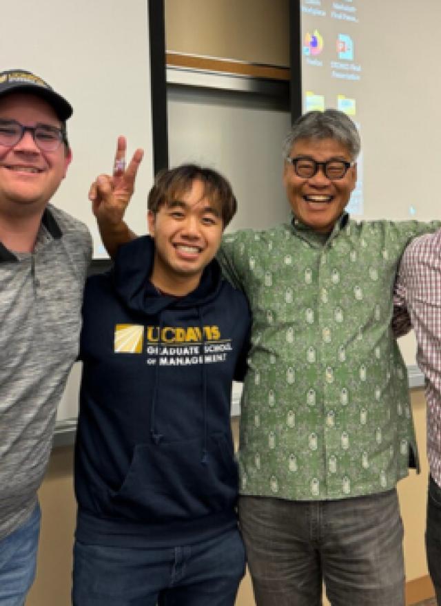 Timothy O'Brien, Alex Schultz, and Kyle Wong, and Lecturer Marc Lowe in a classroom