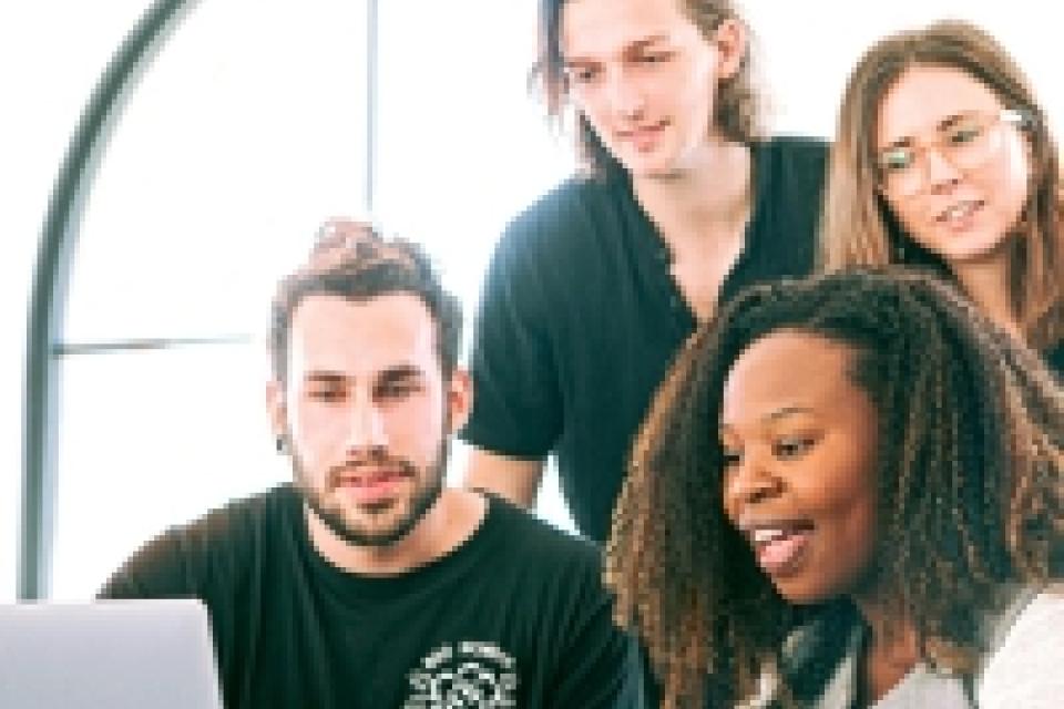 four people in front of a laptop